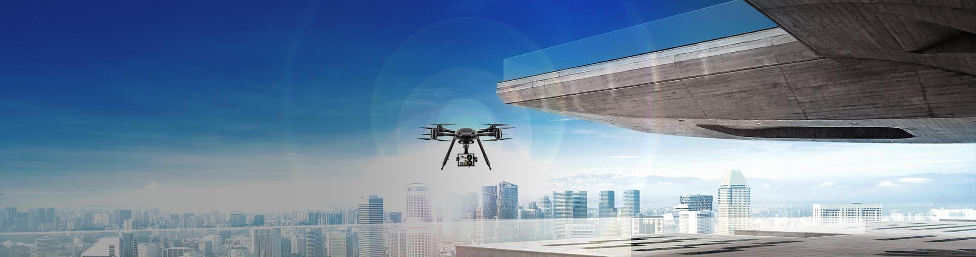 Drone seen from the front flying over a tall building and the city in the background with sun and strong light in the background.