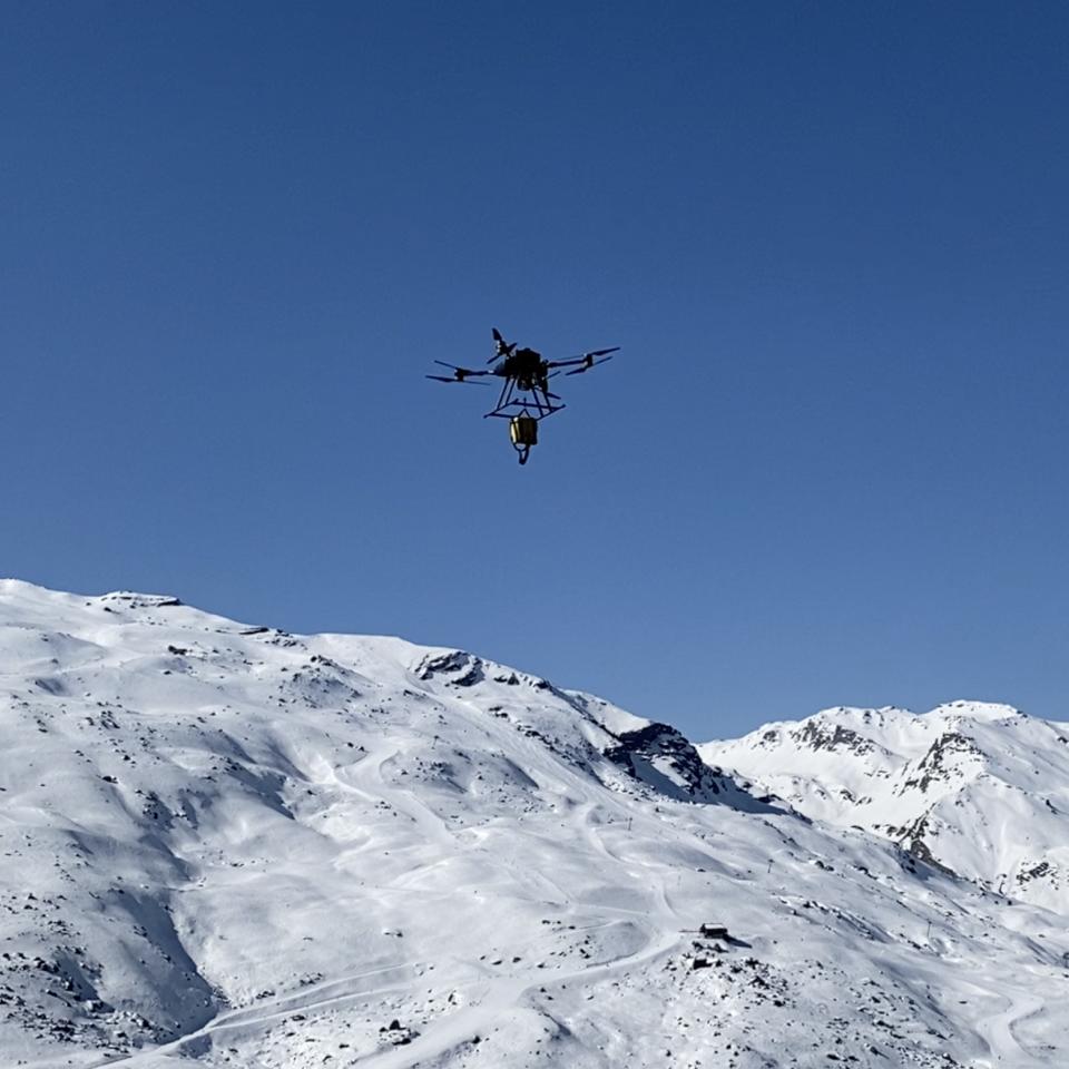 Drone transporting vital equipment near an icy mountain.